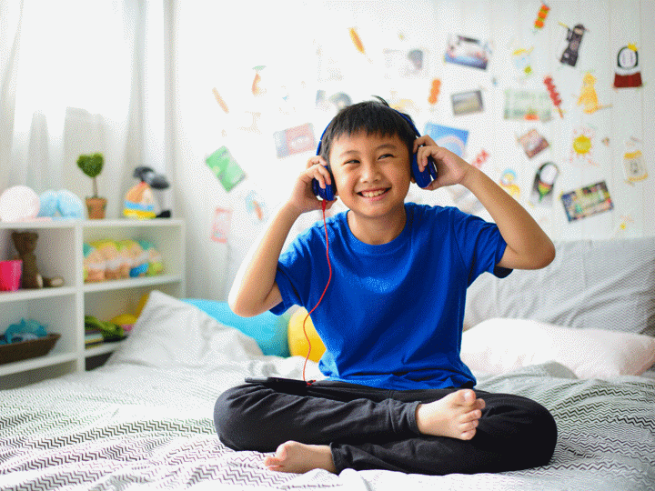 Asian boy using headphones and smiling happy while listening music