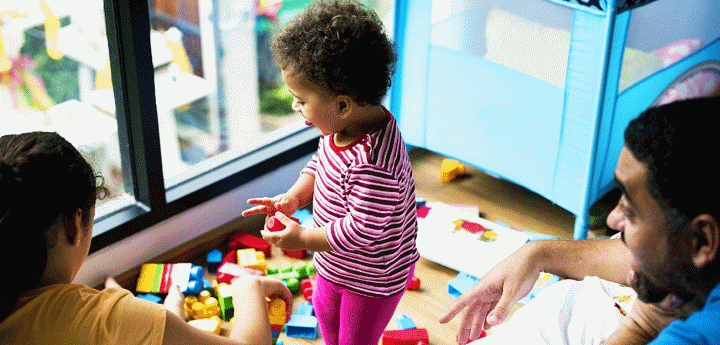 child standing playing with toys with parents watching